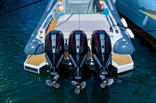 Three outboard powerful boat engines on the transom of a boat in the harbor