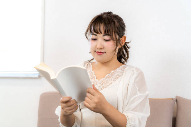 istock Young woman reading a book at home 1432623331