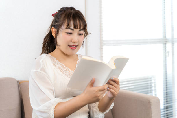 istock Young woman reading a book at home 1432624150