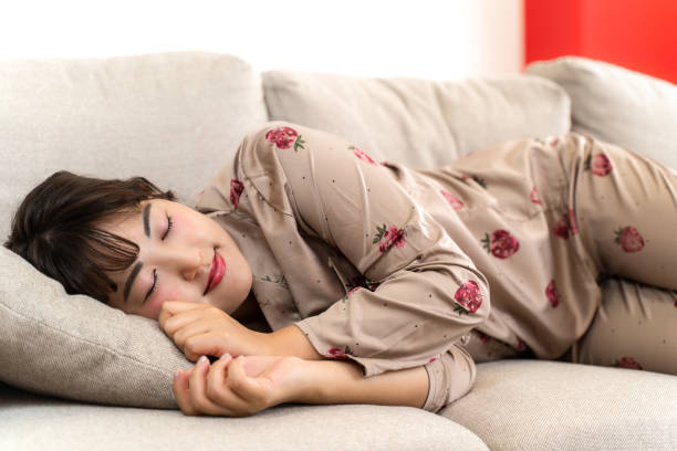 istock Young woman in pajamas relaxing on sofa 1432626870