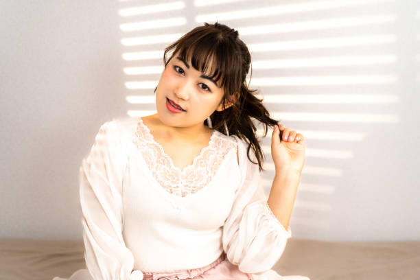 istock Young woman on bed receiving sunlight through blinds 1432627410