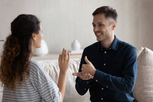 istock Smiling man and woman with deafness using signs for communication 1432628763
