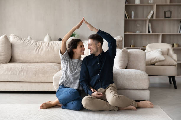 A couple looking at each other with their hands mimicking a house