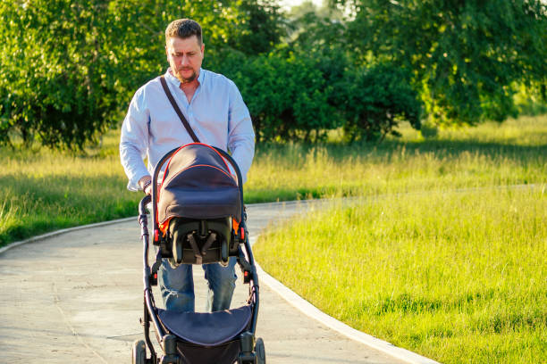istock handsome man is walking with a baby in a stroller in the park 1432636274
