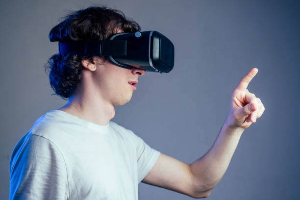 istock portrait of a young man in virtual reality points points his finger gray wall background. The concept of games in the mask of virtual reality 1432637067