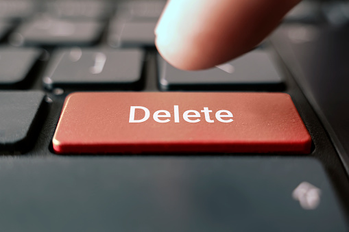 male finger pressing red delete black keyboard button