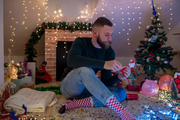 istock young man with a beard sitting at home near the Christmas tree 1432645487