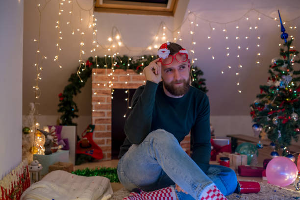 istock young man with a beard sitting at home near the Christmas tree 1432645740