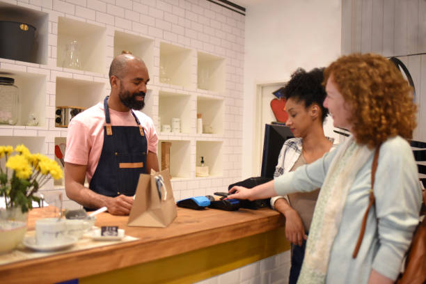 istock friends paying in a store with mobile phone 1432648840