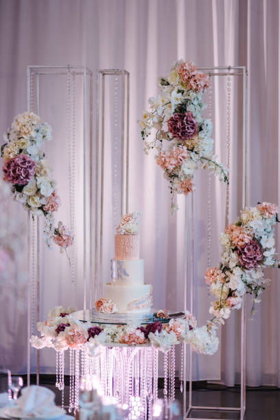 istock Delicious wedding reception. Birthday cake on a background party. Wedding cake on a background of an arch decorated with flowers for a banquet. Celebration concept. Trendy Cake. 1432655261