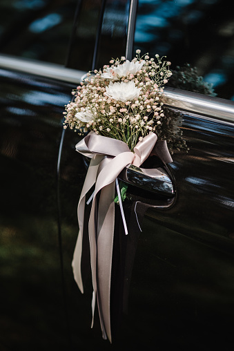 Flower decor on black car. Wedding car with beautiful decorations.