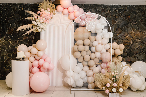 Decoraciones de cumpleaños: globos, guirnaldas y decoración para una pequeña fiesta de bebés en un fondo de pared. Concepto de bautismo de celebración. Texto del bebé. Pastel de moda. photo