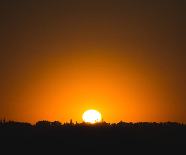 istock Dawn orange bright hot sun disk rising over the forest, warm cloudless morning 1432658752