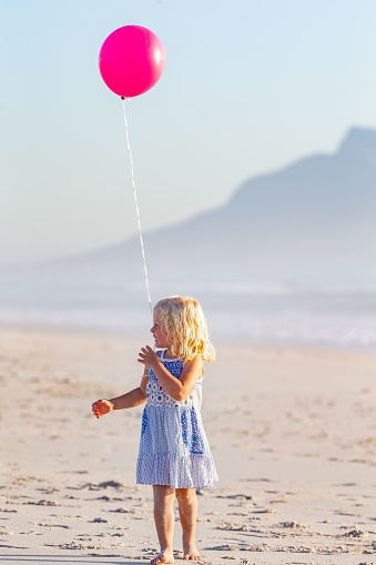 Little girl enjoying a day on the beach with her pinky balloon