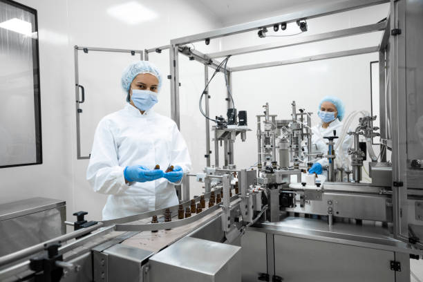 Two fully equipped coworkers in protective workwear seen in a pharmaceutical laboratory
