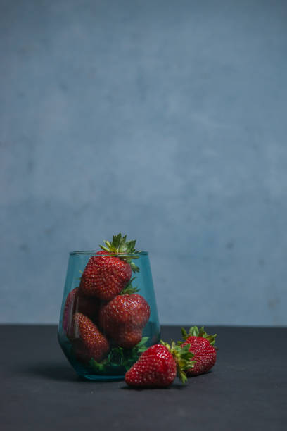 Fresh strawberries in a beautiful glass on a dark blue background. tonic. selective focus. atmospheric summer background, mood. advertising summer parties. promotional summer offers.