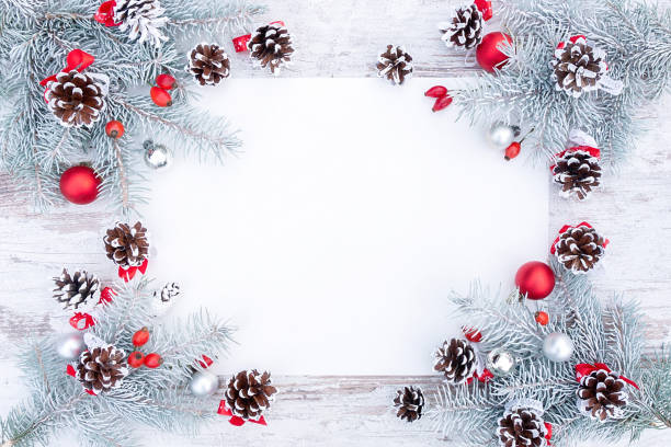 istock White and red Christmas frame or wreath with blank paper, pine cones and Christmas tree decorations flat lay top view. Stylish Christmas background with snow-covered spruce branches and copy space. 1432667996