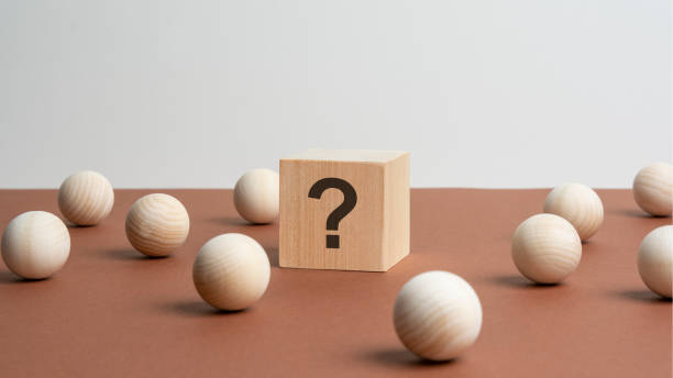 istock wooden cube with a question mark surrounded by wooden balls on a brown table background 1432668346