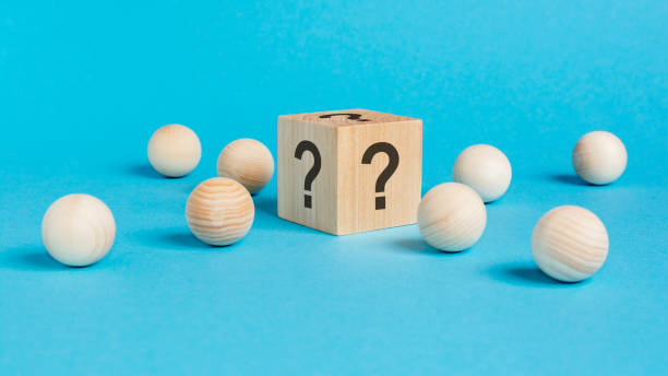 istock wooden cube with a question mark surrounded by wooden balls on a blue table background 1432671679