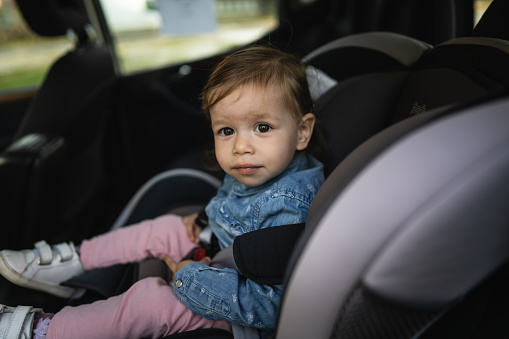 One girl small caucasian toddler female child sitting in the safety car seat chair 18 months old transportation concept copy space
