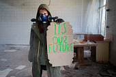 Environmental pollution, ecological disaster, nuclear war, woman in gas mask with a banner that says: it's our future. post apocalypse. Care for future generations.