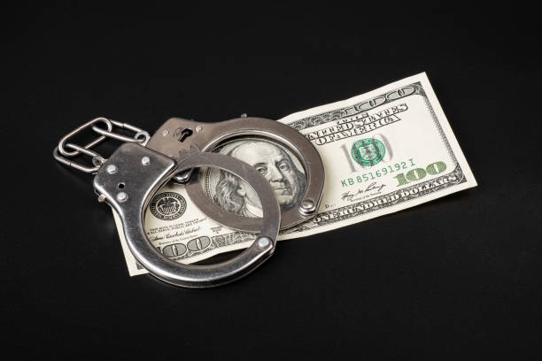 istock fraud and money laundering, 100 dollars and handcuffs on dark background 1432678585