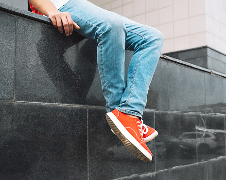 Selfie of male legs in black leather boots and green color pants on the pavement.\nMan taking photo of his foots stand on blank floor, top view. Design mock up. A male wear shoes with casual dress and watching down on road street.