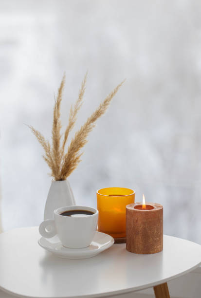 istock cup of coffee with burning candles  on white table by window on winter 1432685531