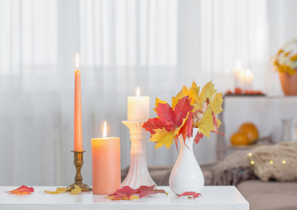 istock burning candles with autumn decor on white table at home 1432689070