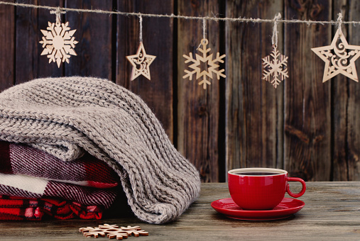 stack of plaids, cup of tea  and Christmas decorations on old wooden background