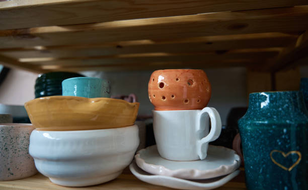 istock Glazed earthenware cups, plates and vases stand on wooden shelves 1432692554