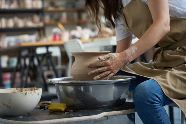 istock Craftswoman sits at the potter wheel and forms clay vase 1432692648