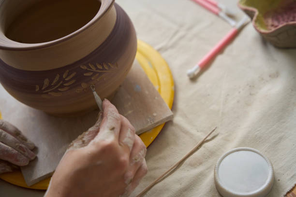 istock Craftswoman sits at table and works with loop on vase 1432692674