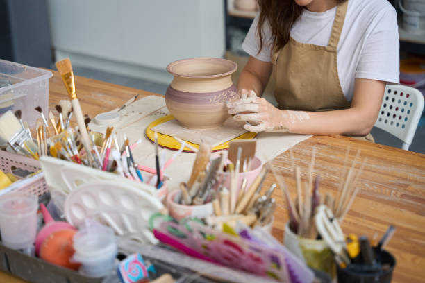 istock Craftswoman applies a decorative pattern to a clay pot 1432692680