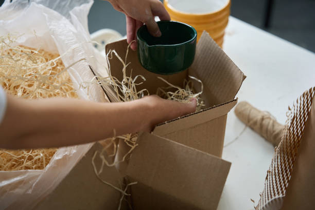 istock Woman packing a beautiful ceramic cup into a cardboard box 1432692691