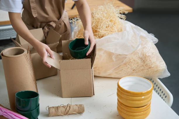 istock Woman putting green ceramic cup into cardboard box 1432692693