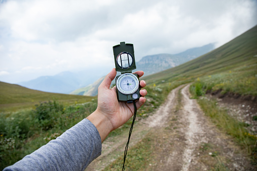 nature concept, man hand compass in mountain road