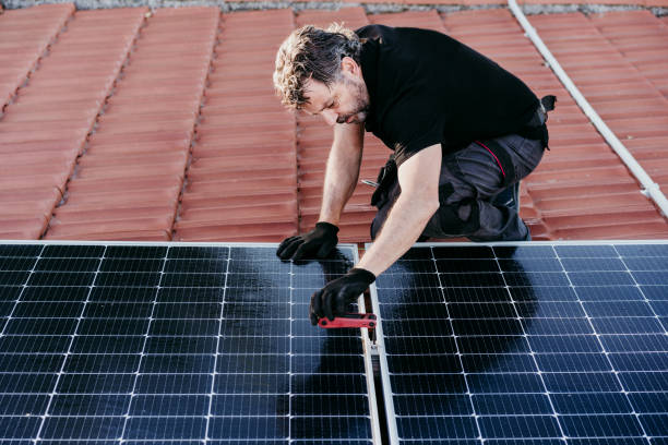 mature Technician man assembling solar panels on house roof for self consumption energy. Renewable energies concept stock photo