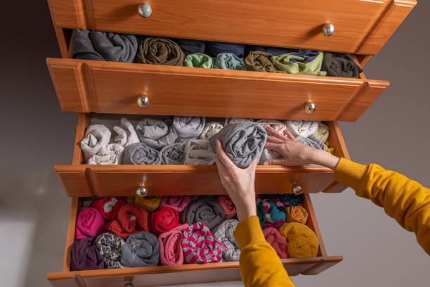 istock Cleaning and sorting clothes in the wardrobe Japanese method. Open chest drawers with  vertical storaged twisting clothes. View from above. 1432700144