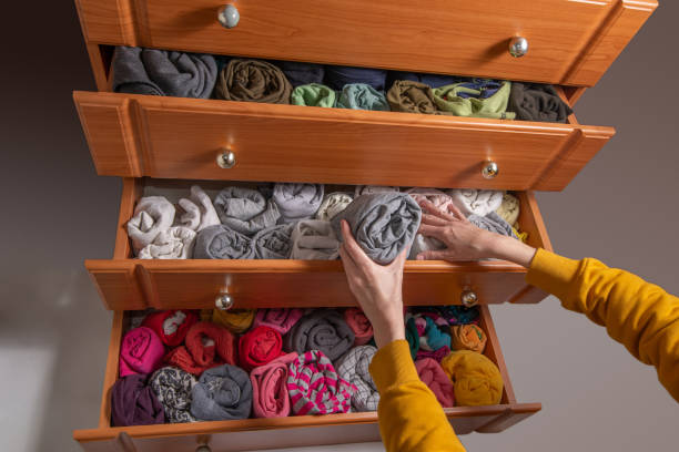Cleaning and sorting clothes in the wardrobe Japanese method. Open chest drawers with  vertical storaged twisting clothes. View from above. stock photo