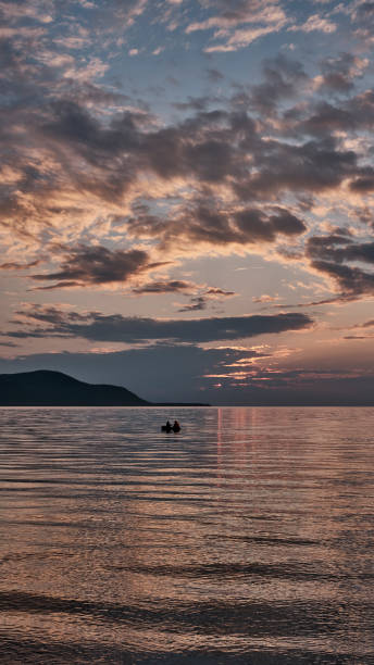 istock Colorful summer sunset on bay. Scenic dramatic clouds on sky. Boat with two people 1432700401