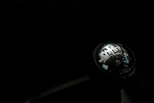 Gear shift lever of the car in the dark background. Image with copy space. Close up of top of gear stick in car interior