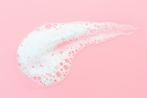 Smear of cleansing facial foam close up on a pink background top view.