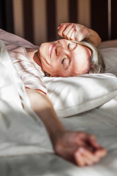 istock Happy middle aged woman sits on bed and stretching arms 1432706967
