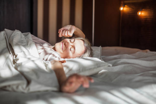 istock Happy middle aged woman sits on bed and stretching arms 1432706969