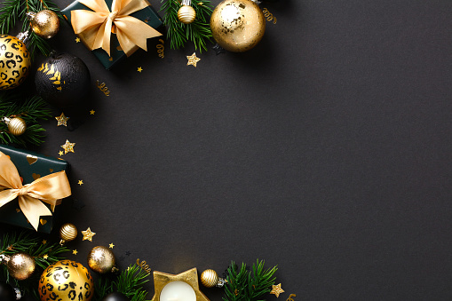 Luxury Christmas greeting card template. Golden Christmas balls, gift boxes, decorations on black background. Flat lay, top view, copy space.