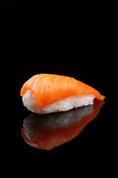 istock Sushi with rice and salmon on black background with reflection 1432709123