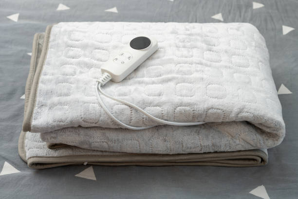 folded electric blanket with controller on the bed at horizontal composition stock photo