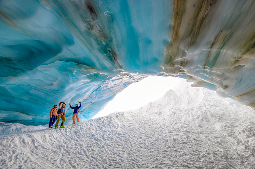 Skiers standing at the entrance to ice cave in Whistler, BC, Canada. One of them is taking picture of the group.