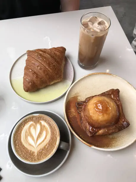 Kouign-amann tabled with a croissant, hot coffee and iced-coffee